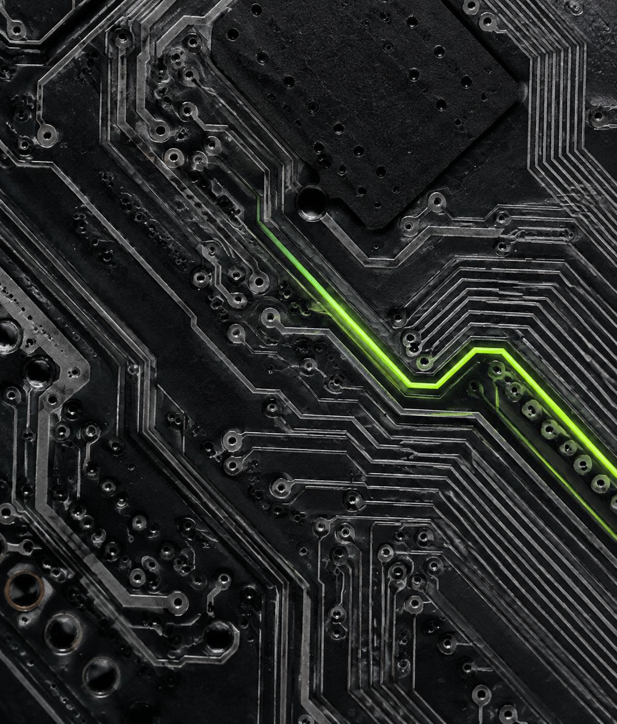 Macro photograph of a dark circuit board with a single glowing lime trace